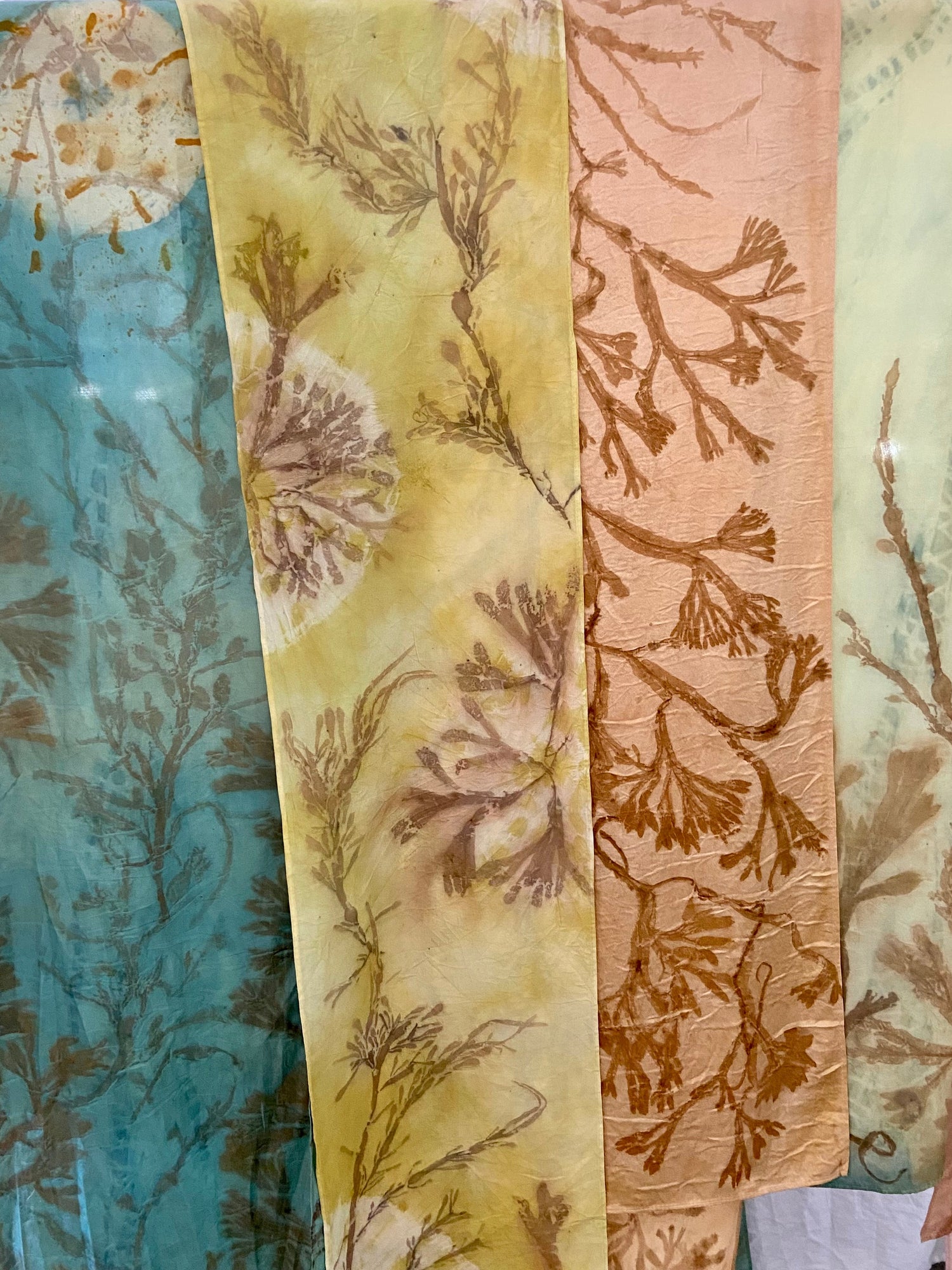 Colorful naturally dyed silk scarves with delicate seaweed prints displayed at the Jamestown Arts Center Holiday Art Market in Jamestown, Rhode Island — eco-printed textiles handcrafted by local artist Sasha Azbel of Sashoonya.
